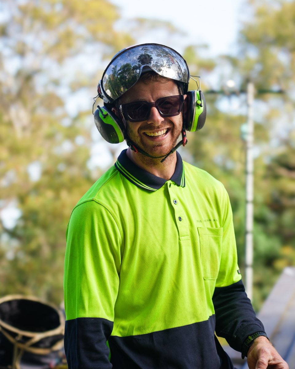 Alex Price, lead arborist at The Living Canopy, smiling on site in climbing helmet and hi-vis